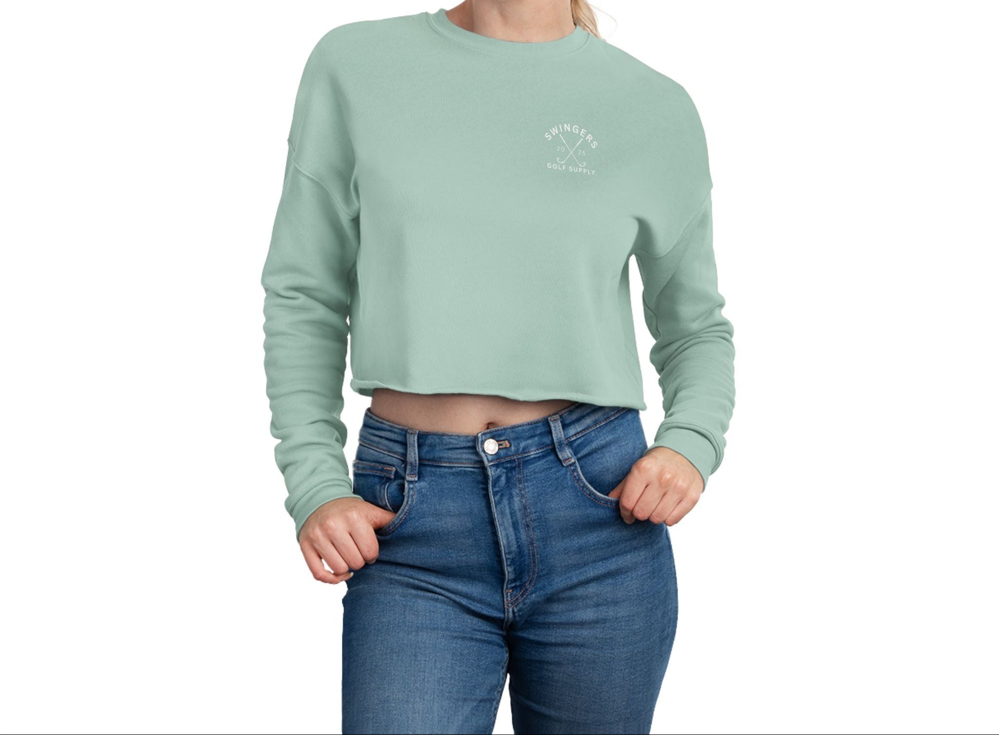 Woman wearing a light green cropped sweatshirt and blue jeans on a white background