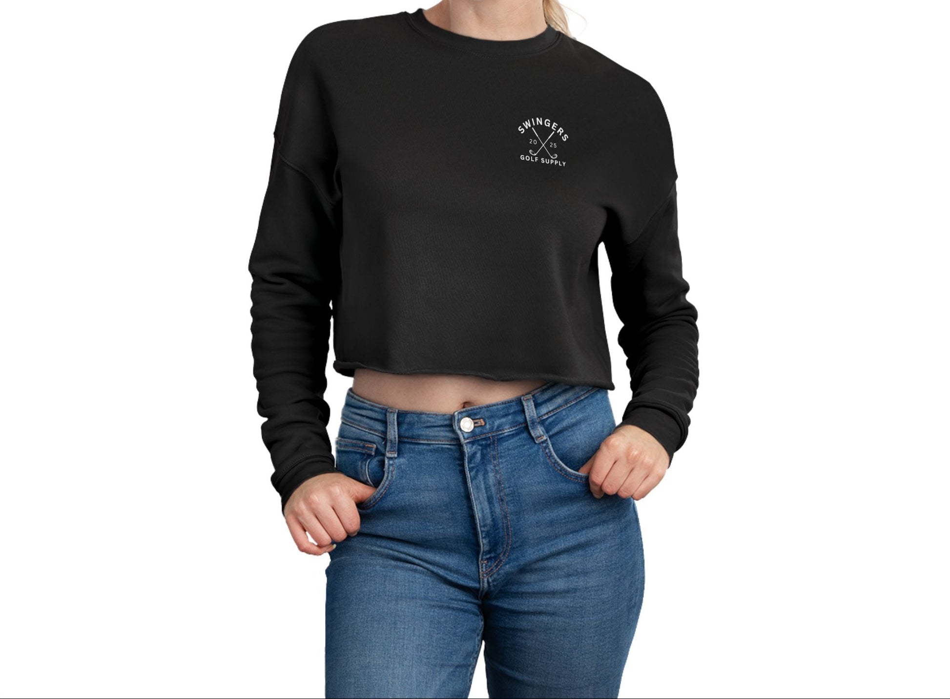 Woman wearing a black cropped sweatshirt with a logo and blue jeans on a white background